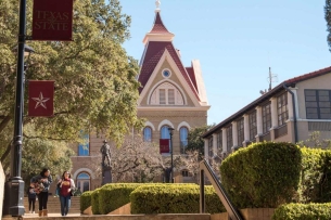 Two students walk through a college campus outside during the day